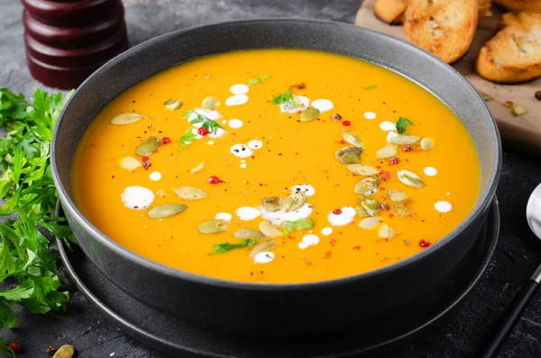 Pumpkin Soup, Tasty Homemade Pumpkin, Sweet Potato or Carrot Soup in a Bowl on Dark Rustic Background