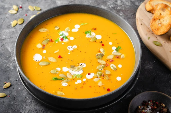 Pumpkin Soup, Tasty Homemade Pumpkin, Sweet Potato or Carrot Soup in a Bowl on Dark Rustic Background
