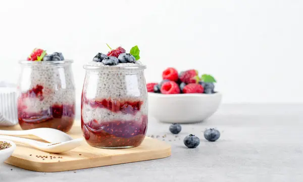 stock image Healthy Chia Pudding in a Glass with Raspberry Jam and Fresh Berries on Bright Background