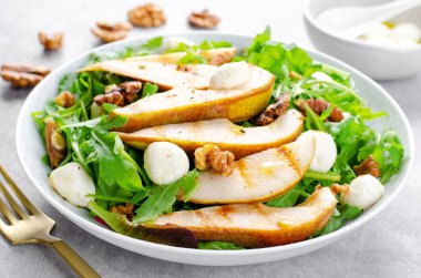 Izgara Armut Salatası, Armut, Arugula, Mozzarella İncileri, Ceviz ve Parlak Arkaplanda Giyinme Üzerine Taze Salata