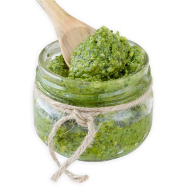 Beyaz arka planda ahşap kaşıklı pesto sosu.