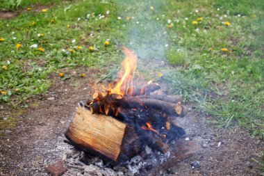 Yangın evin yakınındaki çimlerin üzerinde yanıyor ve tütüyor..