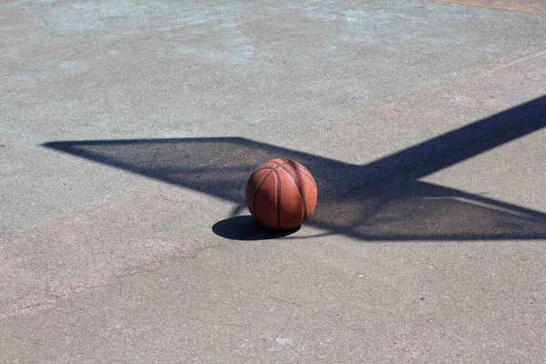 The shadow of a basketball backboard on a yard sports ground