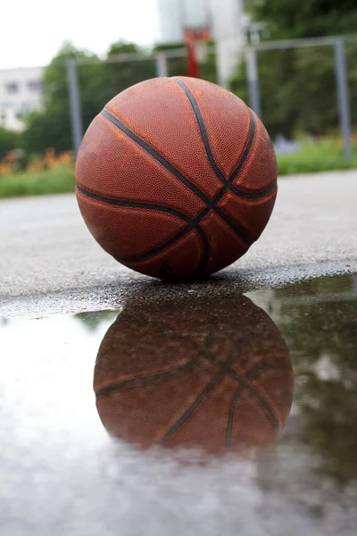 水溜りの反射を持つストリートコートのバスケットボールボール — ストック写真