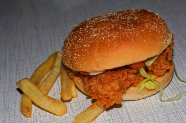 Lezzetli hamburger ve patates kızartmasının yanında bir parça tavuk eti.