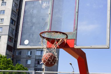 Basketbol topu bir sokak sporları sahasında sepetin içine uçuyor.