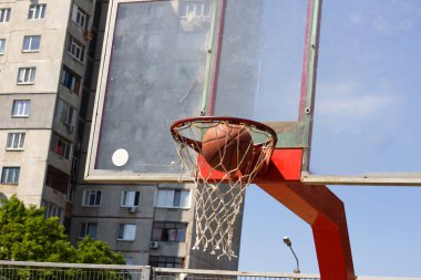 Basketbol topu bir sokak sporları sahasında sepetin içine uçuyor.