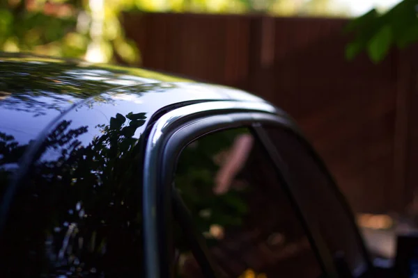 Φωτογραφία Ενός Μαύρου Αυτοκινήτου Από Πλάι Όμορφες Αντανακλάσεις Φυτών — Φωτογραφία Αρχείου