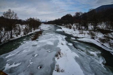 Ukrayna Karpatlarının nehir kenarındaki dağ köyü, kış manzarası