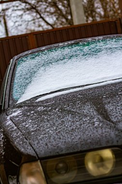 Eski siyah bir Avrupa arabasının üzerine erimiş kar damlaları