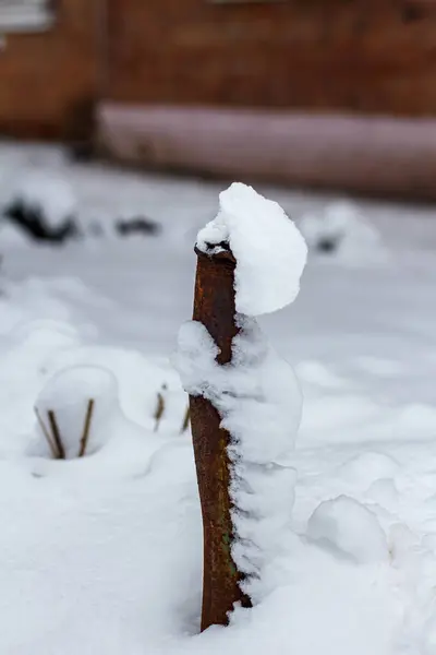 A rusty iron pipe sticks out of the ground in winter. Pipe in the snow.