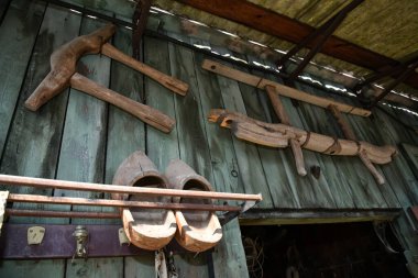 Köydeki ahşap bir barakanın duvarında çeşitli aletler var.