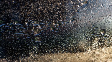 Bir arabanın ön camında erimiş kar damlaları