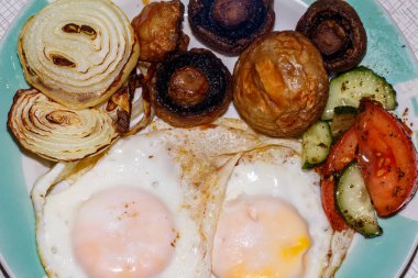 Lezzetli bir kahvaltıda kızarmış yumurta, mantar ve sebze salatası.