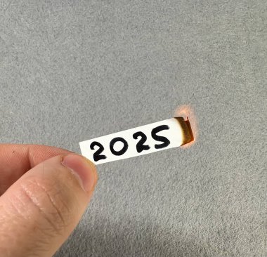 2025 rakamları yanan bir kağıt parçasında