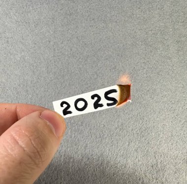 2025 rakamları yanan bir kağıt parçasında
