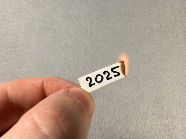 2025 rakamları yanan bir kağıt parçasında