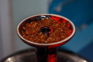 Yakın planda meyveli tütünlü kırmızı nargile kasesi. Kil kasede nargile tütünü.