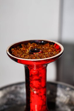 Yakın planda meyveli tütünlü kırmızı nargile kasesi. Kil kasede nargile tütünü.