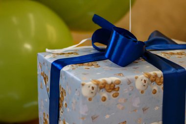 Arkaplanda mavi kurdele ve yeşil balonlar olan hediye kutusu. Bir çocuk için hediye paketi.