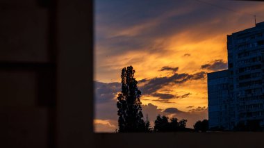 Harkiv 'de günbatımı. Şehir manzarası. Portakal Gökyüzü. Pencereden bak. Ağaç Silueti. Akşam bulutları. Ukrayna Şehri. Harkiv Binaları. Atmosferik Gökyüzü.