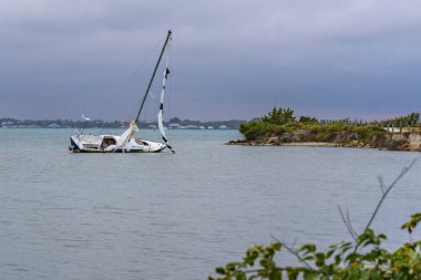 A sailboat beached on sandbar on it's side in the water.