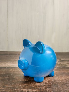 Mavi domuz kumbarası ahşap masanın üzerinde para kazanmak ya da tasarruf etmek için 