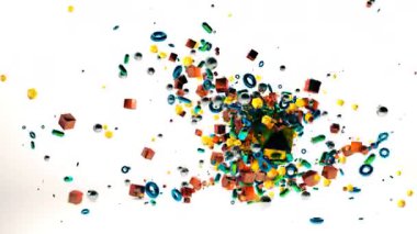 Beyaz zemine saçılmış üç boyutlu küçük nesnelerin renkli patlaması. Değişik renkleri ve şeffaf yüzeyleri neşe dolu bir hareket hissi veriyor.