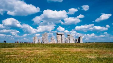 Stonehenge, Salisbury, Wiltshire, İngiltere 'deki tarih öncesi taşların üzerinde hareketli bir zaman kayması gün ışığını yakalıyor ve sürükleniyor.