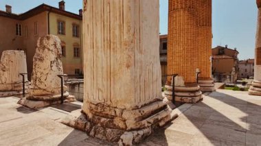 BRESCIA, İtalya, 20 Temmuz 2024 - Antik Dorik sütunlar ve dağınık mimari parçalar Tempio Capitolino Roma Harabeleri, Brescia, Lombardy, İtalya 'da modern sokaklara karşı duruyor