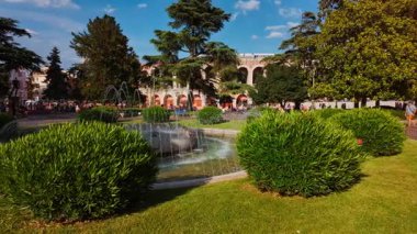 VERONA, İtalya, 12 Temmuz 2024 - Piazza Bra, Verona, Veneto, İtalya bahçeleri, tarihi saraylar ve Roma amfitiyatrosunun gölgesinin altındaki açık hava kafeler sergilenen bir şehir meydanı