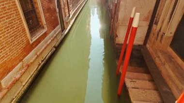 Venedik, İtalya 'daki ünlü kanallardan birinin çarpıcı görüntüsü. İlginç binalar, güçlü yansımalar ve canlı yeşil su. Venedik, 472 köprü ile birbirine bağlı 126 adadan oluşan bir takımadadır.