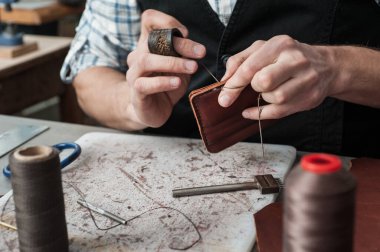 Yakın plan dikişler. Ürünün el dikimi. Deri ürünlerin üretimi, çanta dikimi, cüzdan, debriyaj.