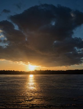 Güzel dramatik gökyüzü, buzla kaplı gölün üzerindeki bulut, buzda gün batımının yansıması.