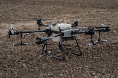 TERNOPIL REJON, UKRAINE - 06 Mayıs 2023 - Yeni insansız hava aracı püskürtücü DJI AGRAS T30 saban tarlasının arka planında, paketleri açma, hassas tarım, en son tarım
