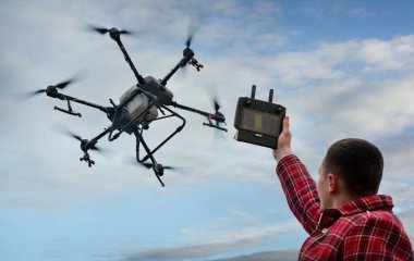 Erkek çiftçi, uzaktan kumandalı bir tarımsal püskürtücü insansız hava aracı, bağlantı ve parametrelerin kontrolüne sahip.