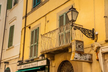 İtalya, Pisa - 20 Temmuz 2013: Pisa 'da üzerinde tabela, retro saat, balkon ve fener bulunan bir sokak parçası
