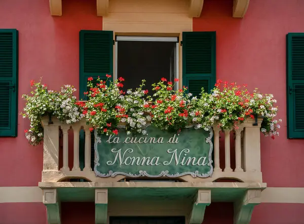 balcony with geranium flowers and traditional Italian shuttered windows and handmade sign - Nina\'s grandmother\'s kitchen