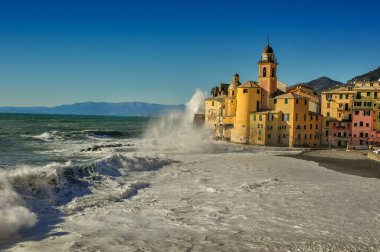 Camogli sahilinde büyük dalgalar ve Santa Maria Assunta Bazilikası, Cenova, İtalya.
