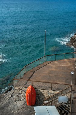 Akdeniz kıyısında dinlenmek için bir sahil terası, kırmızı bir filika, tahtalardan yapılmış bir iskele.