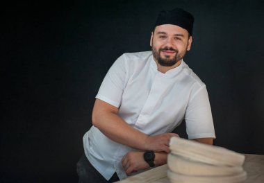 Bereli bir aşçının portresi ya da fırıncı, önlüklü ve beyaz gömlekli genç bir erkek, yemek pişiriyor. Yemek pişirme konsepti.