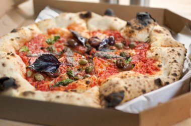 Pizzayı ançüezli, domates soslu, fesleğenli, kaparili, zeytinli kapat.