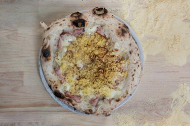 Beşamel soslu Napoli Gateau pizzası, patates, jambon, mortadella, mozzarella, hindistan cevizi, parmesan, ahşap masa üzerinde un, üst manzara.