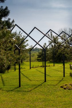 Bir dizi grafik metal yapılar geometrik desen oluşturur, çam ağaçları arasında doğal bir çevrede bir manzara tasarımı.