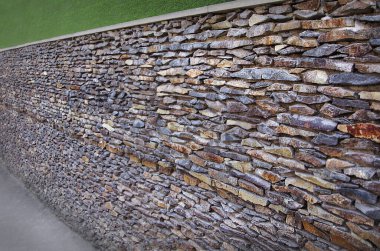 Duvar, çeşitli gölgelerden, manzara tasarımından oluşan dikdörtgen doğal taşlarla kaplıydı.