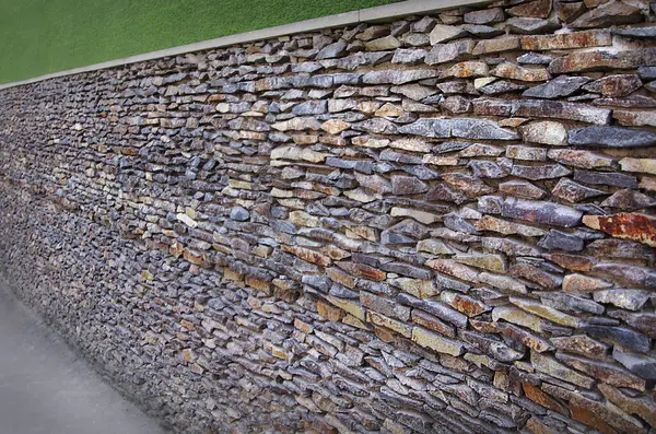 Duvar, çeşitli gölgelerden, manzara tasarımından oluşan dikdörtgen doğal taşlarla kaplıydı.