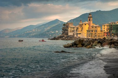 Turkuaz dalgalı, turkuaz bir sahil Akdeniz ve renkli evler, Camogli, Ligure, İtalya 'da bir dağ zeminine karşı kilise kulesi.