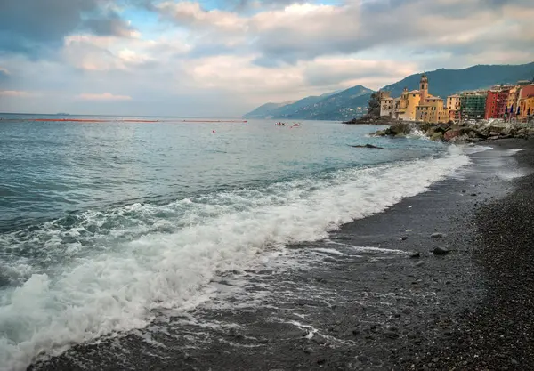 Camogli, İtalya, turkuaz dalgalar ve renkli evlerle Akdeniz kıyısındaki bir dağ zeminine karşı.
