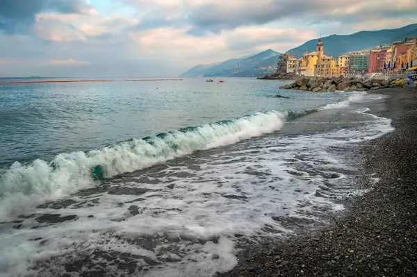 İtalya 'nın Camogli kentinin turkuvaz dalgaları ve renkli evlerle dolu güzel sahili bir dağ zeminine karşı. Akdeniz kıyısının huzurlu atmosferi.