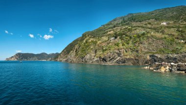 Uçurumlarında kristal berrak su ve yeşil terasları olan Cinque Terre kıyıları. Kayalık kıyılarda bir yelkenli teknesi olan sakin bir koy İtalyan uyumu ortamı yaratır..